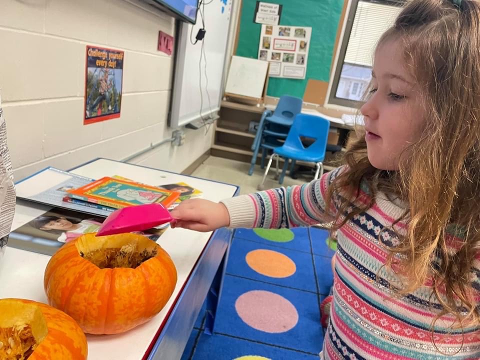Student pouring items into pumpkin