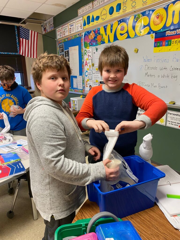 Students filling a sock with rice to make a sock snowman