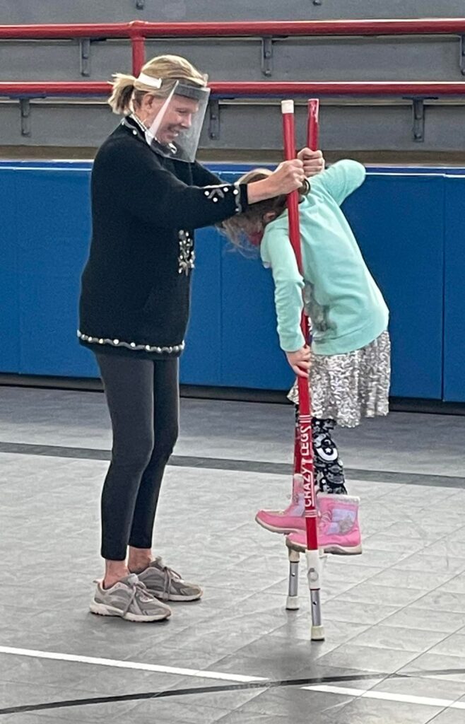 Linda Kirkeberg helps a student use stilts